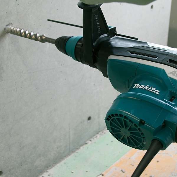 Makita HR5212C rotary hammer drilling into a concrete wall with an SDS-MAX bit
