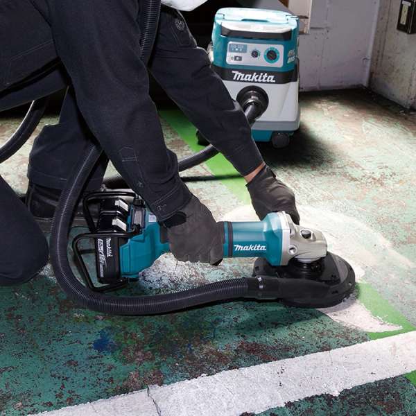 Makita DGA701ZU 充電式角向磨光機接駁吸塵機於地面進行打磨作業