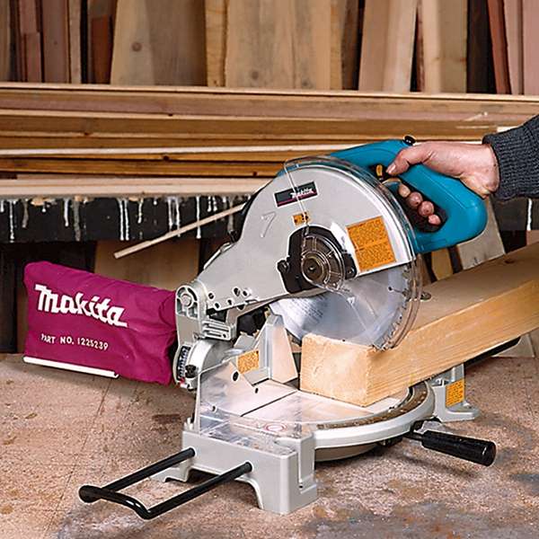 Makita LS1040N miter saw with dust bag cutting timber in a workshop