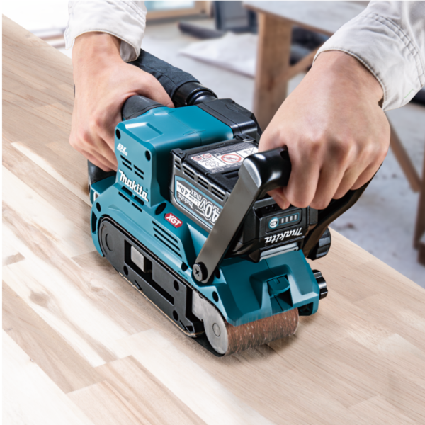 Operator sanding a wooden board with the Makita BS001GZ01 cordless belt sander