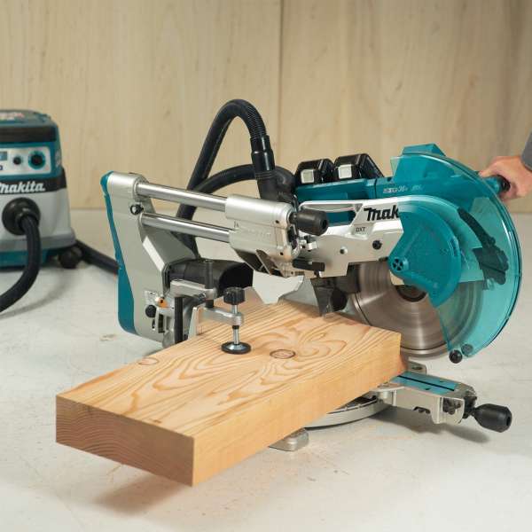 Makita 牧田 DLS211Z 充電式滑動複合斜斷鋸於工作枱上切割木材，並接駁集塵器