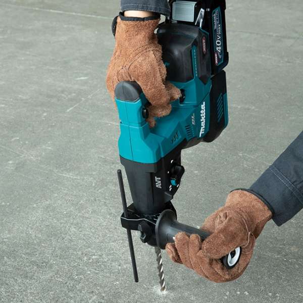 工人戴上手套雙手握持 Makita HR003GZ 充電式電錘，在混凝土地面上鑽孔