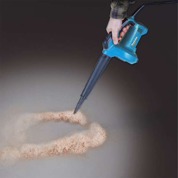 手持 Makita M4000B 吹風機吹走地面木屑的使用情境