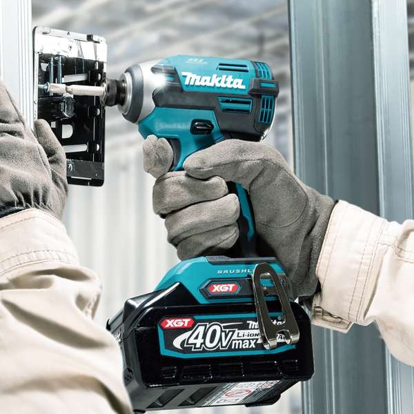 Gloved worker fastening a screw on a metal bracket with the Makita TD003GZ 40V cordless impact driver