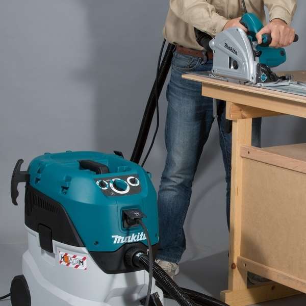 Makita VC4210MX 集塵機以軟管連接電動圓鋸，於工作枱切割木材時同步吸走粉塵