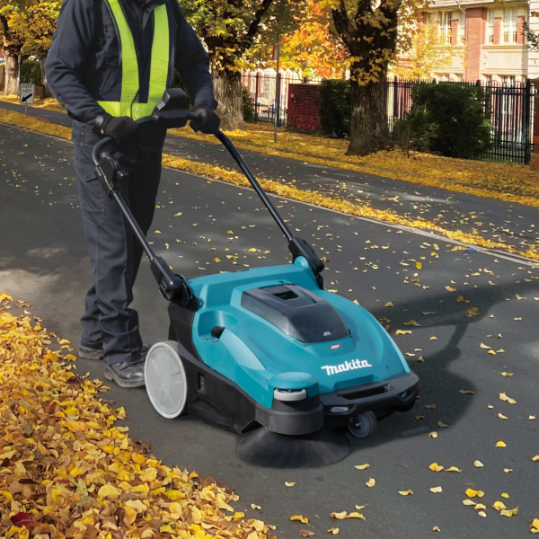 操作員在戶外路面使用 Makita VS001GZ 40V 充電式掃地吸塵機清掃落葉