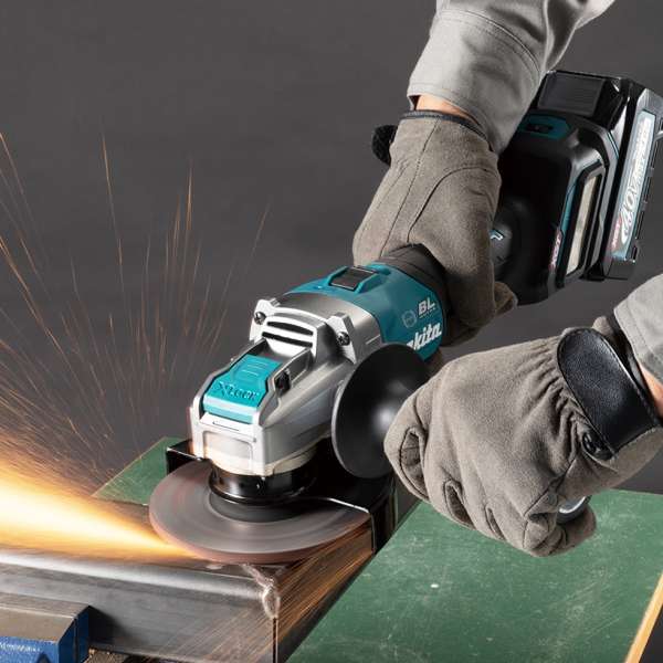Operator grinding a steel workpiece with the Makita GA041GZ cordless angle grinder