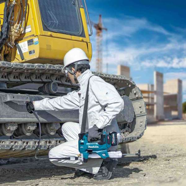 Worker greasing an excavator crawler track with the Makita GP001GZ cordless grease gun