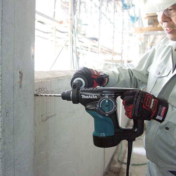 Worker drilling into a concrete wall on site with a Makita HR2810 combination hammer