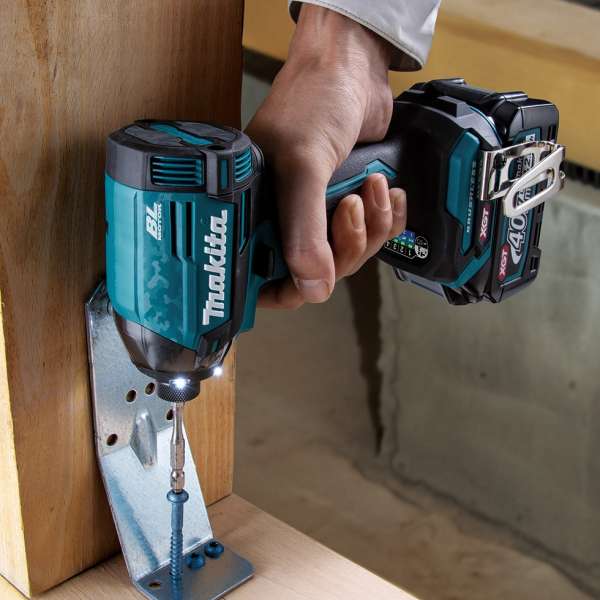 Makita 40V cordless impact driver fastening a screw through a metal bracket into timber on site