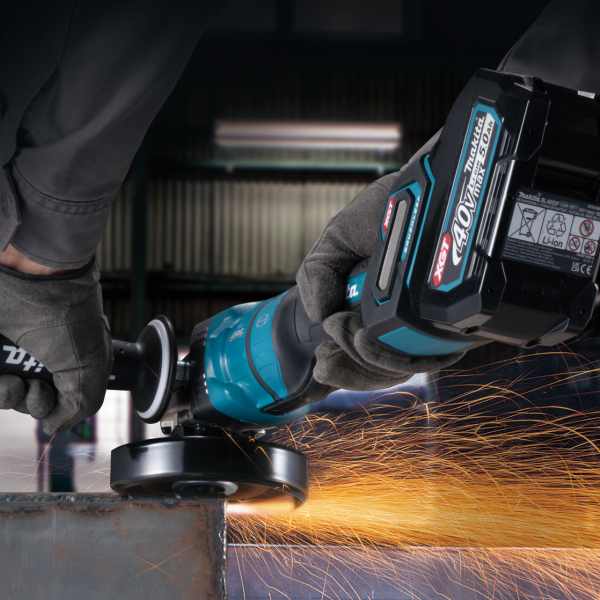Gloved operator cutting metal with the Makita GA048GZ 40V cordless angle grinder, sparks flying