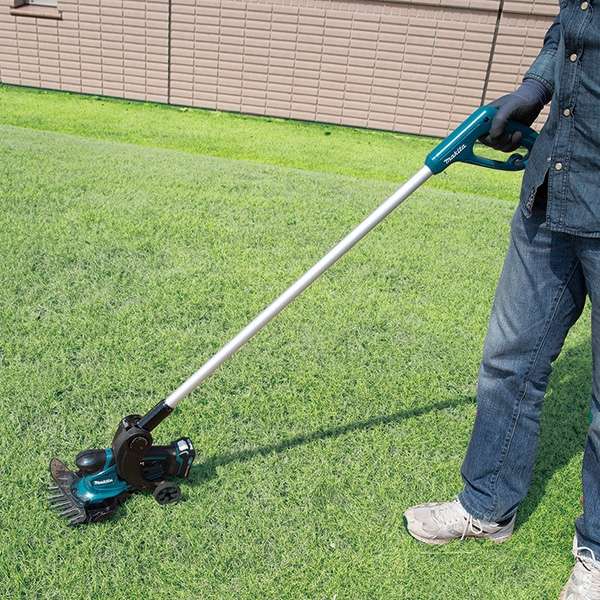 使用者於草地上以 Makita UM600D 充電式剪草機修剪草坪（圖中長柄配件另購）