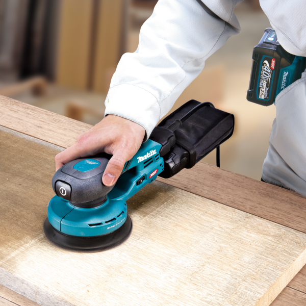 Makita BO003CGZ 40V random orbit sander sanding a wooden surface