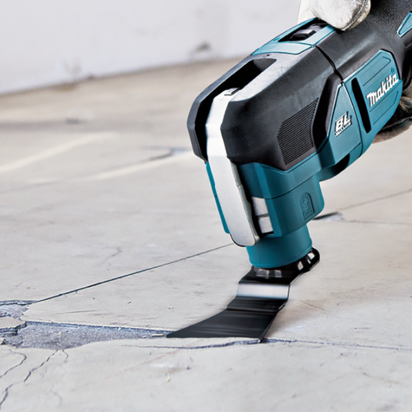 Makita DTM53 multi tool with a scraper blade removing old joint material from a concrete floor