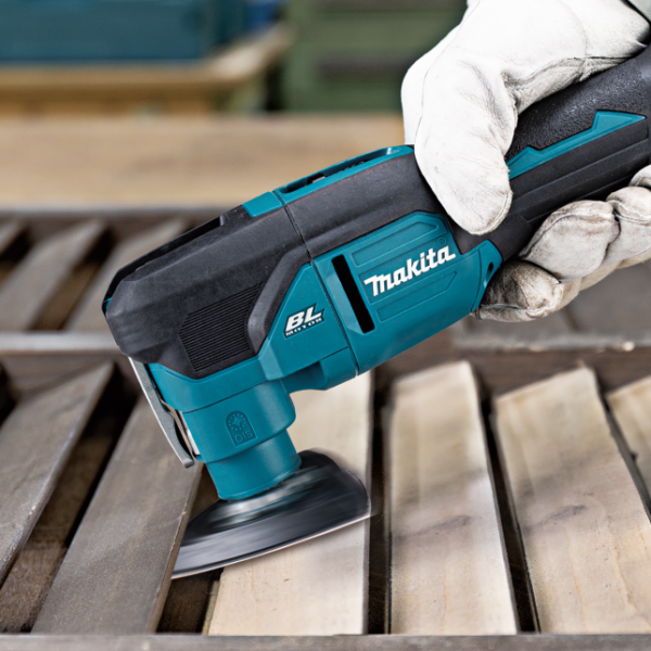 Operator sanding a timber surface with the Makita DTM53 multi tool and sanding pad