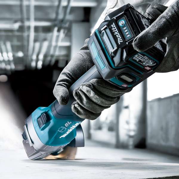 工作人員戴上防護手套，手持 Makita 牧田 GA003GZ 40V 充電式角向磨光機在混凝土表面上作業