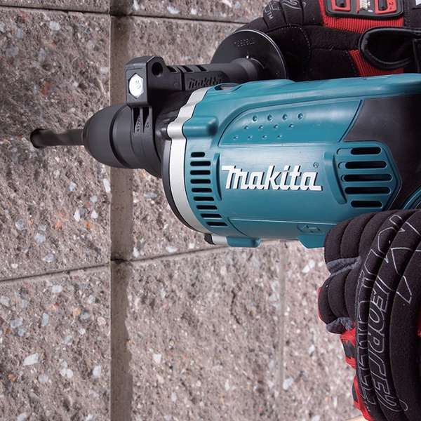 Makita HP1631K hammer drill drilling into a masonry block wall