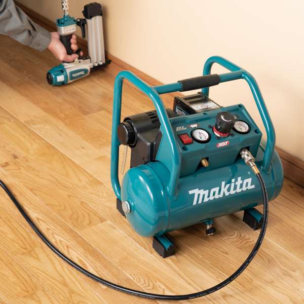 Makita AC001GZ 40V 充電式空氣壓縮機置於室內木地板上，連接氣管配合打釘槍作業
