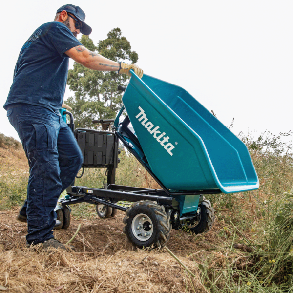 Worker tipping the load of a Makita DCU603Z cordless wheelbarrow on an outdoor slope