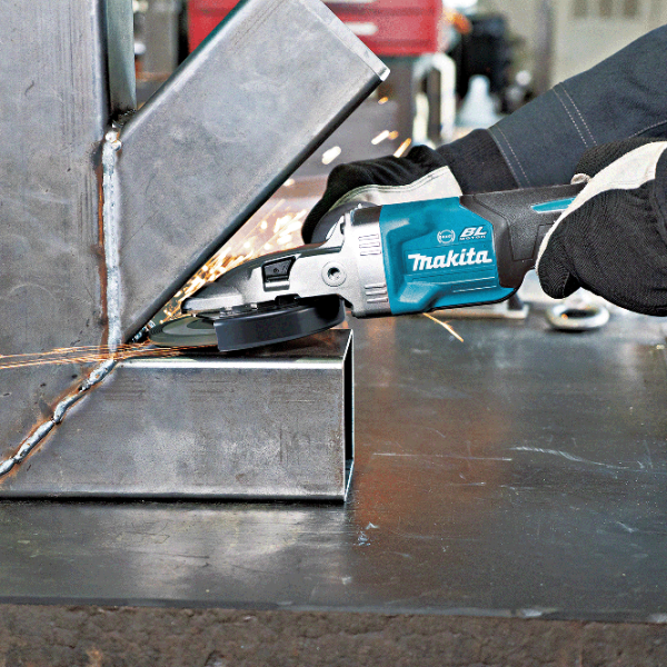 Makita GA056GZ flat-head angle grinder removing weld marks at a narrow steel frame joint