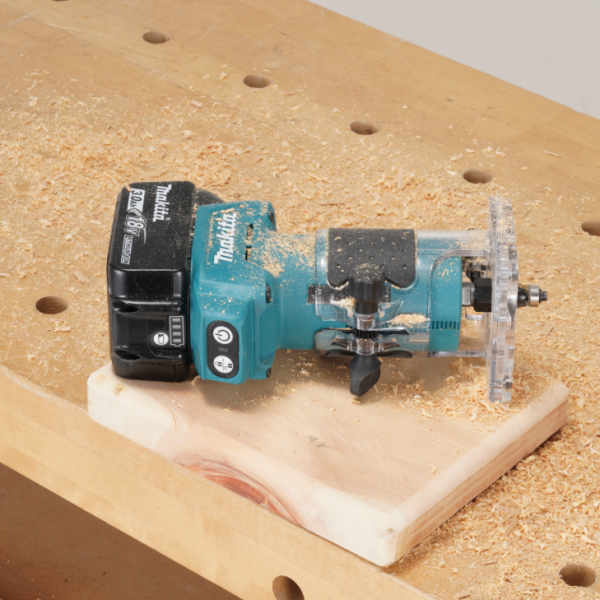 Makita DRT52Z 充電式修邊雕刻機裝上直線導件後放置於工作枱上的木料旁