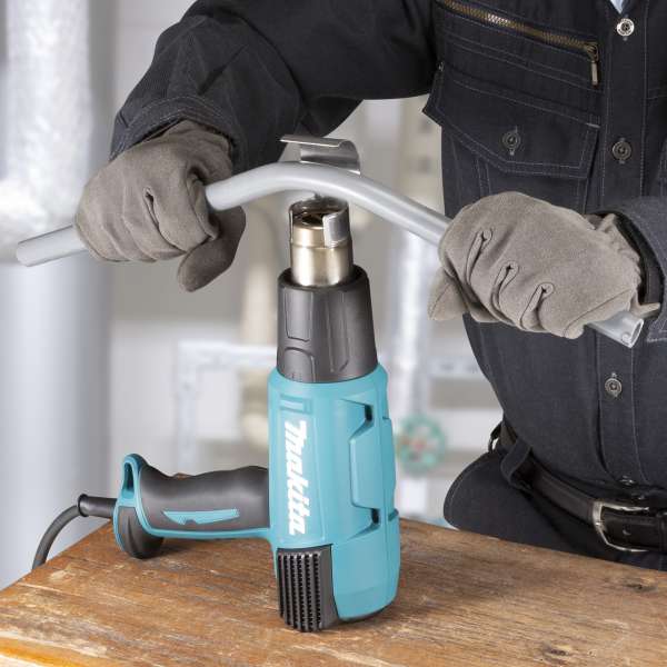 工作人員戴上手套，使用 Makita HG6530VK 熱風槍加熱並屈曲塑膠管