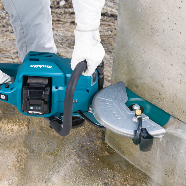 Close-up of the Makita CE003GZ power cutter wet cutting a concrete pipe with the water supply connected