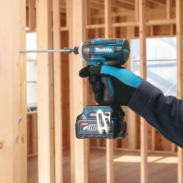 Makita TD004GZ 40V cordless impact driver being used to drive a long screw into timber framing on site