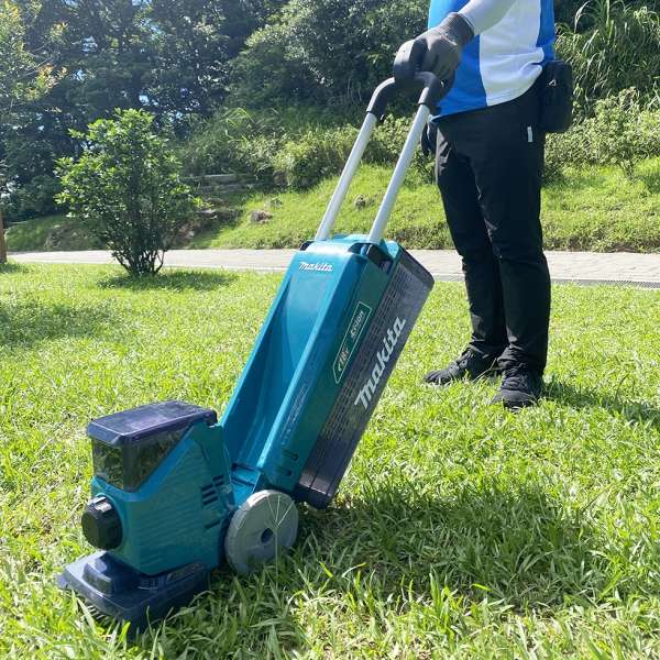 操作人員在草地上使用 Makita DLM160Z 充電小型剪草機修剪草坪
