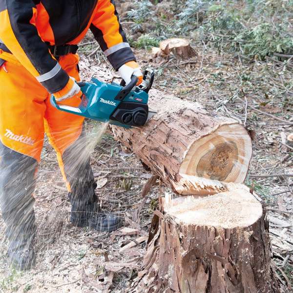 Operator in protective gear cross-cutting a tree trunk outdoors with the Makita UC022GZ 40V cordless chain saw
