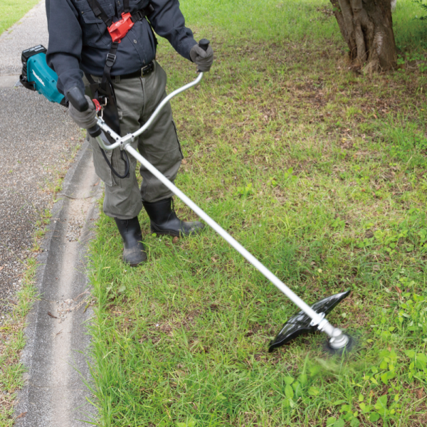操作人員使用 Makita DUR369AZ 充電式割草機於路邊草地修剪雜草