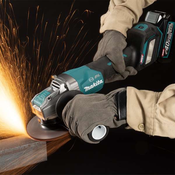 Gloved worker grinding a metal workpiece with the Makita GA044GZ 40V cordless angle grinder, sparks flying