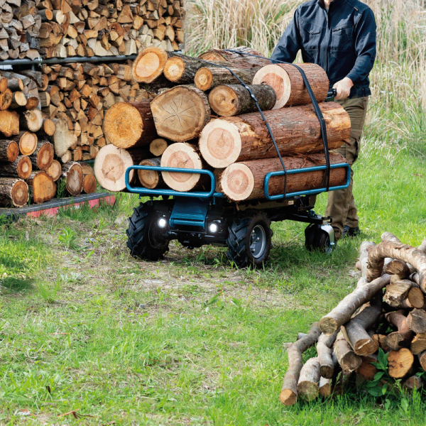 Makita DCU604Z battery powered wheelbarrow hauling logs on grass with its job light on