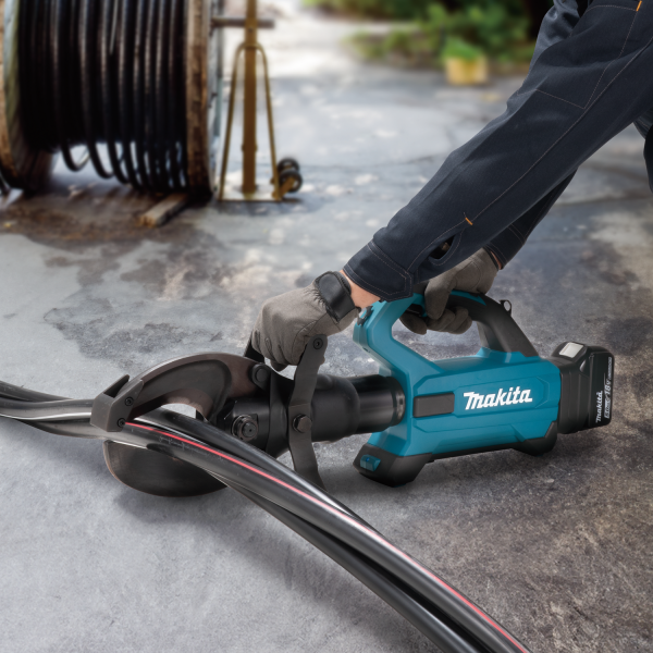 工作人員雙手握持 Makita DTC104ZK 18V 充電式電纜剪斷機，在地面上剪切大直徑電纜