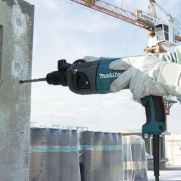 Operator drilling into a concrete wall on site with a Makita HR2230 rotary hammer and SDS-PLUS bit