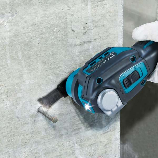 Makita TM001GZ01 multi tool flush cutting a metal nail on a concrete surface