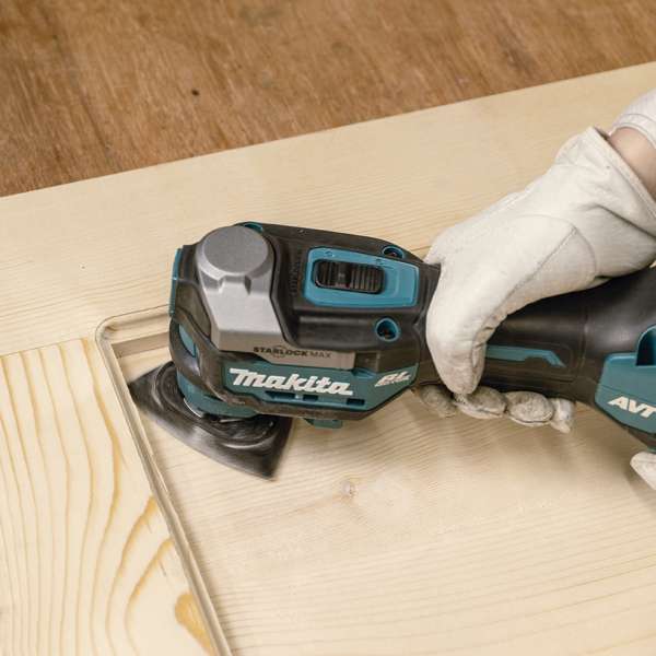 Makita TM001GZ01 multi tool sanding the edge of a timber board with a sanding pad