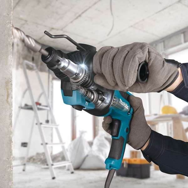 Gloved operator drilling into an indoor concrete wall with the Makita HR2670X5 combination hammer