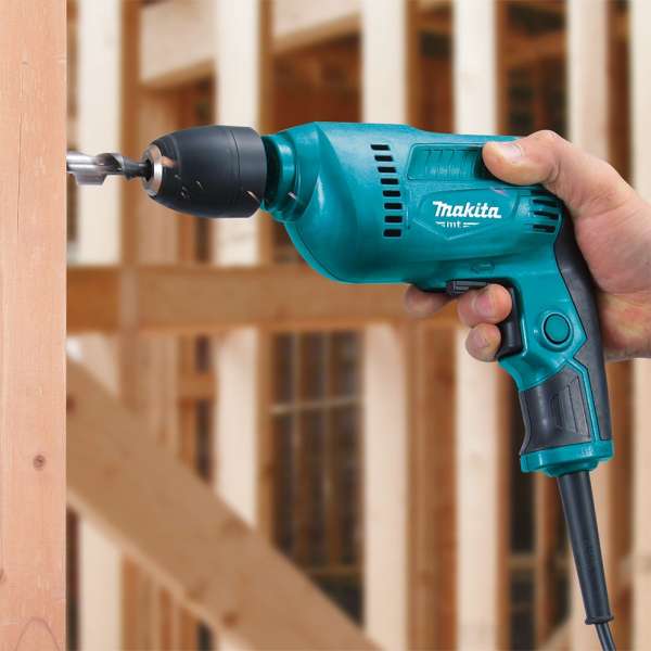 Makita M6002B drill with a bit held in the keyless chuck, drilling one-handed into a timber stud
