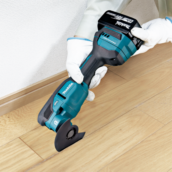 Makita DTM53ZX1 18V cordless multi tool cutting along a skirting board on wood flooring