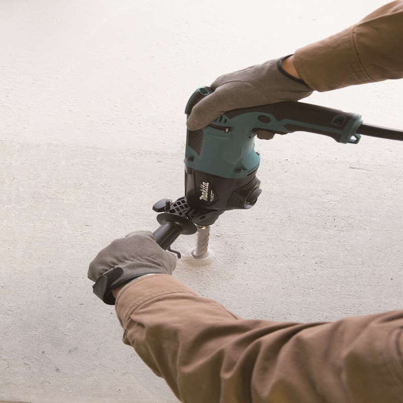 Operator drilling into a concrete floor with the Makita M8701ZB rotary hammer