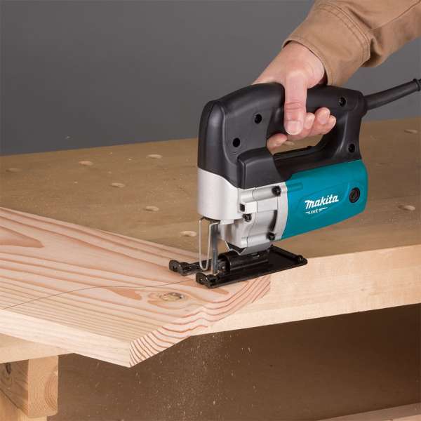 Operator using the Makita M4302B jig saw to cut a timber board on a workbench