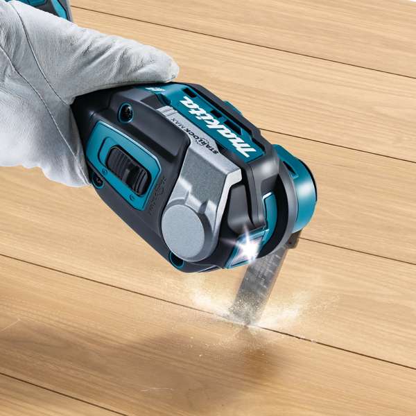 Makita TM001GD201 cordless multi tool plunge cutting into a wooden floor